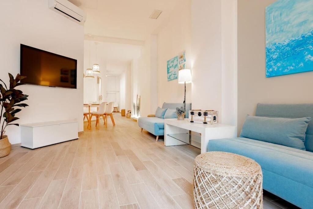 Salón alargado con aire acondicionado, mesa de comedor y televisor de pared