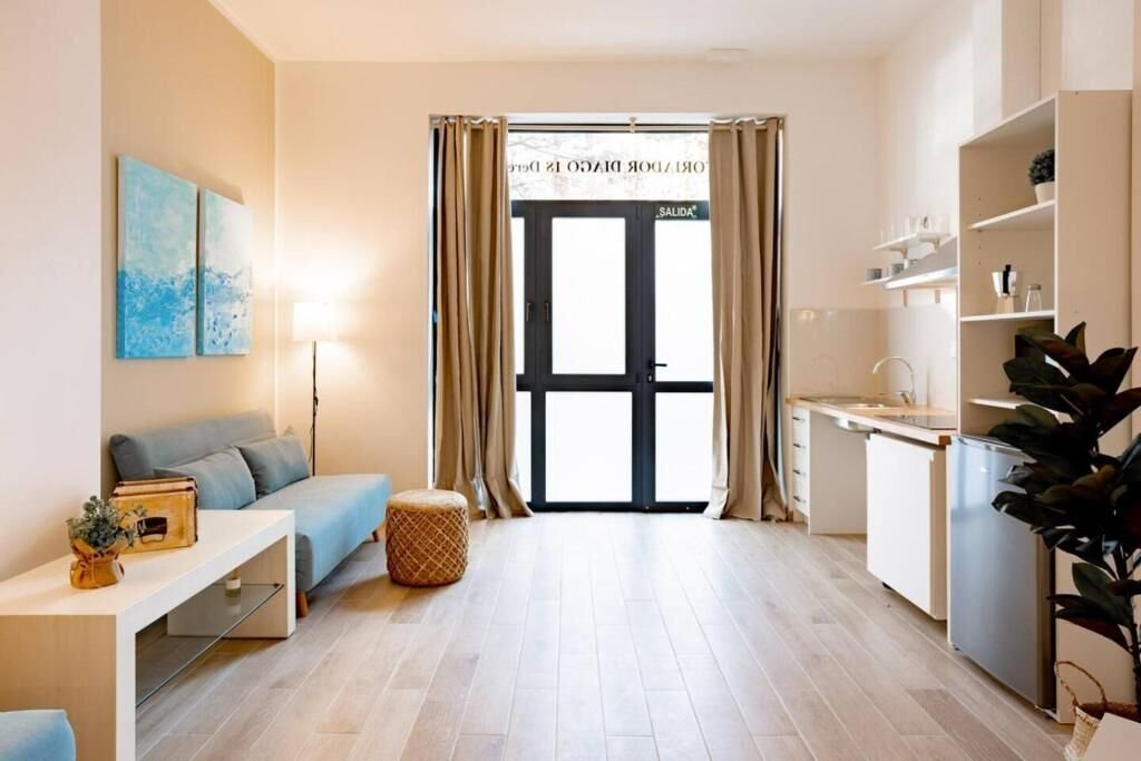 Vista del salón hacia la puerta de entrada acristalada con cortinas