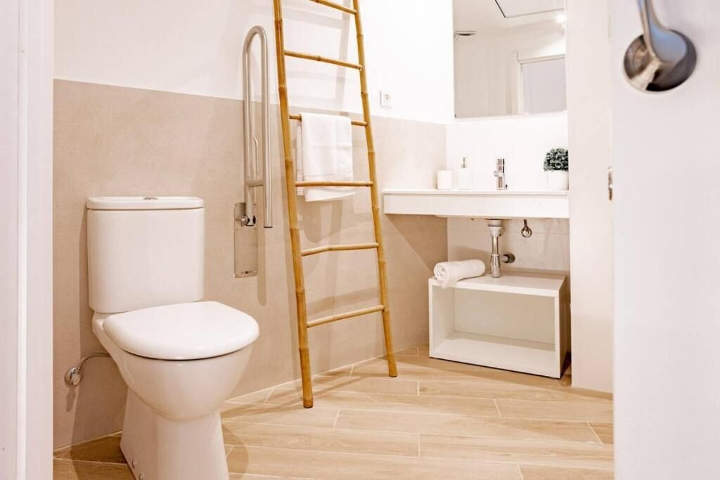 Baño con inodoro, toallero de bambú y lavabo