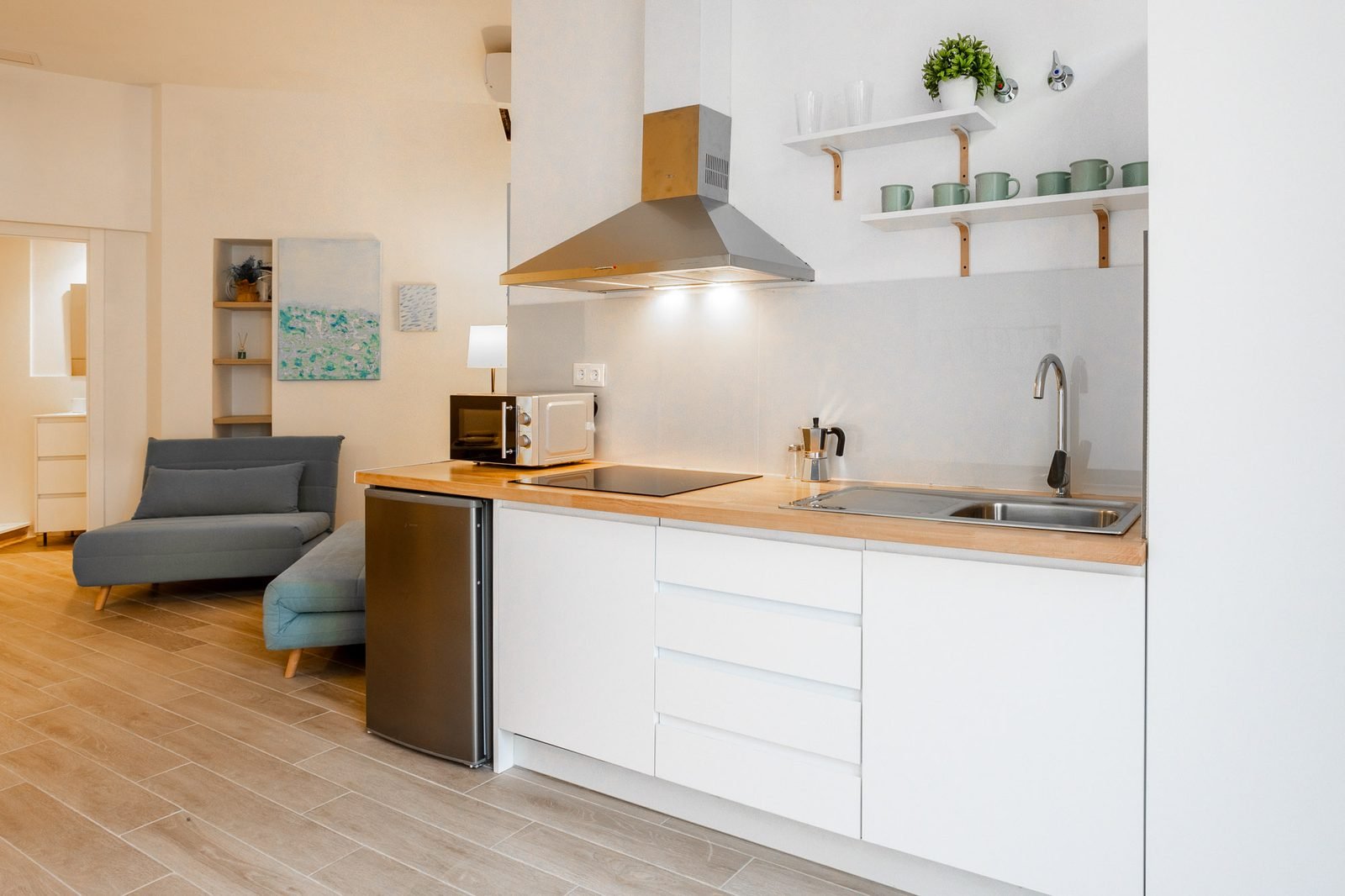 Cocina americana con encimera color mostaza, campana extractora y estanterías con vajilla