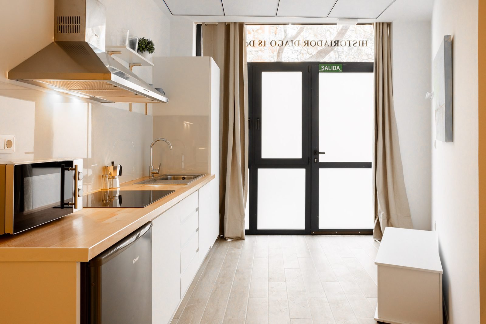 Cocina en pasillo con puerta de salida acristalada a la calle de l'Historiador Diago