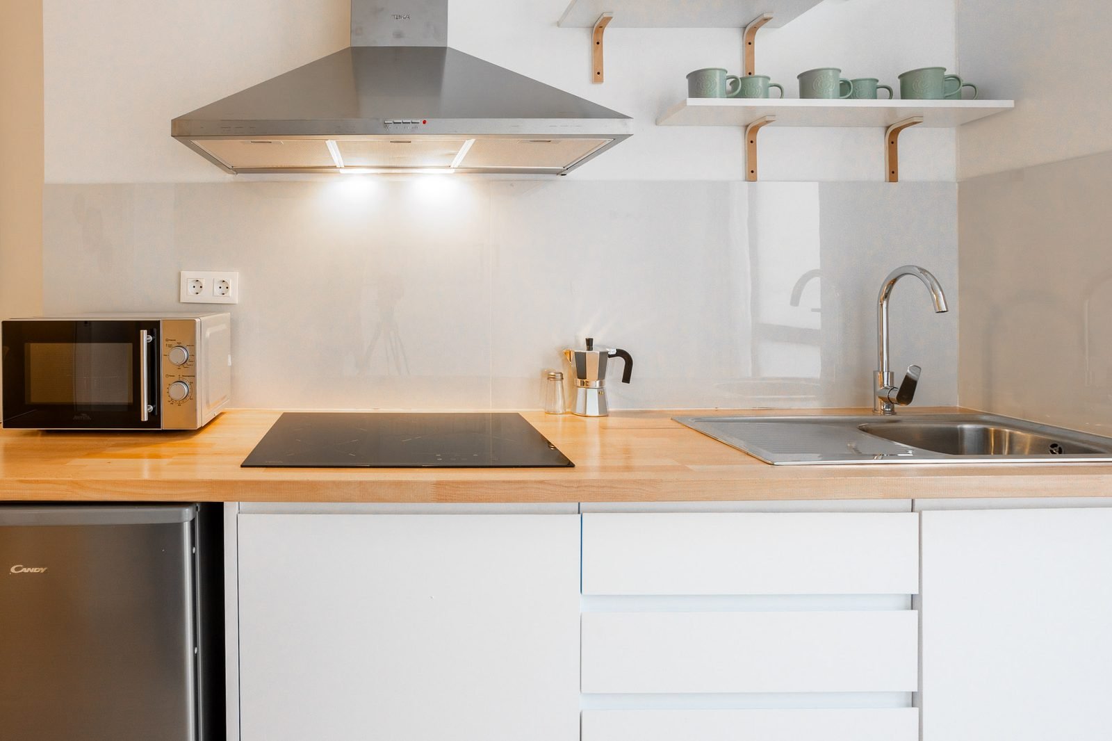 Detalle de la cocina con placa de inducción, fregadero, microondas y cafetera italiana