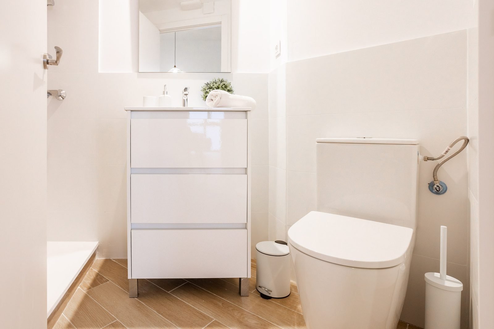 Baño con mueble lavabo blanco, inodoro y ducha