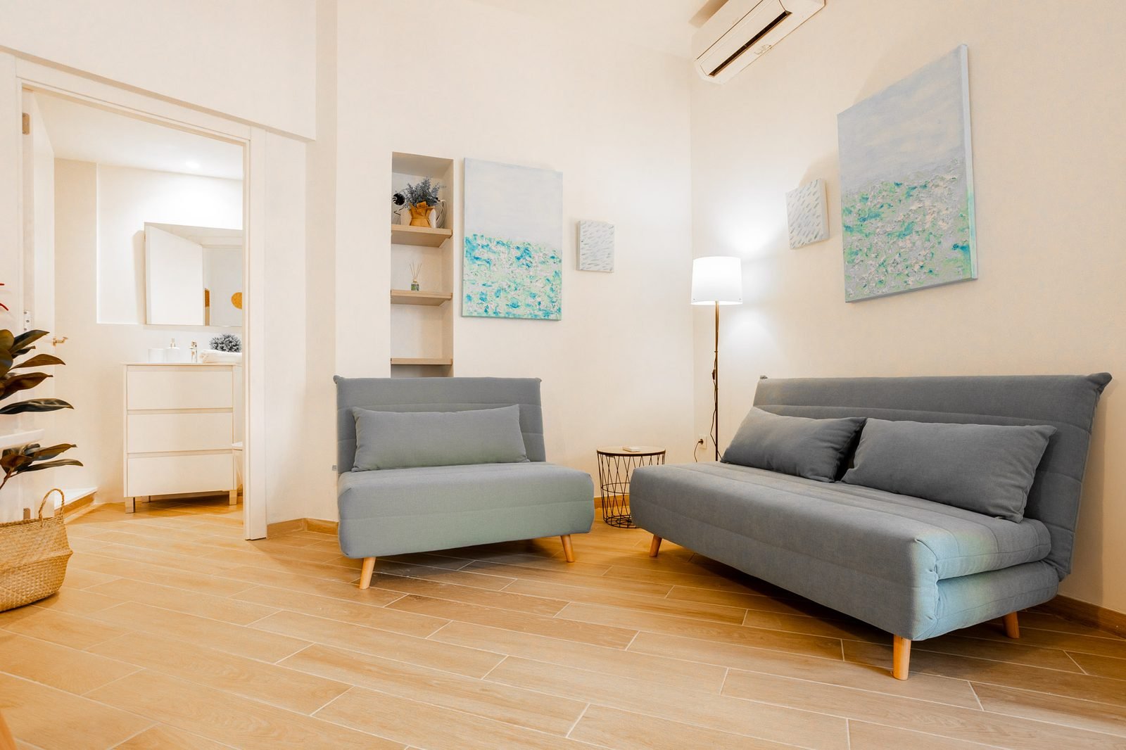 Salón con dos sofás grises, cuadros decorativos y lámpara de pie
