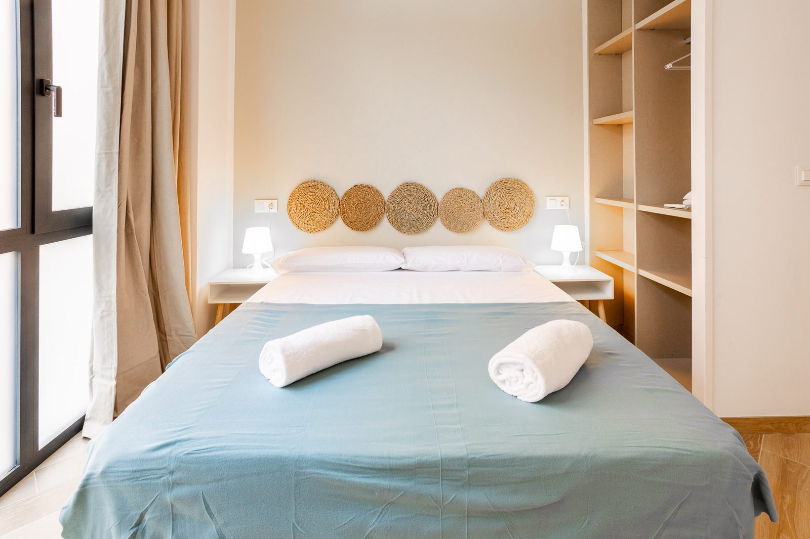 Dormitorio con cama de matrimonio, ropa de cama azul y toallas de cortesía