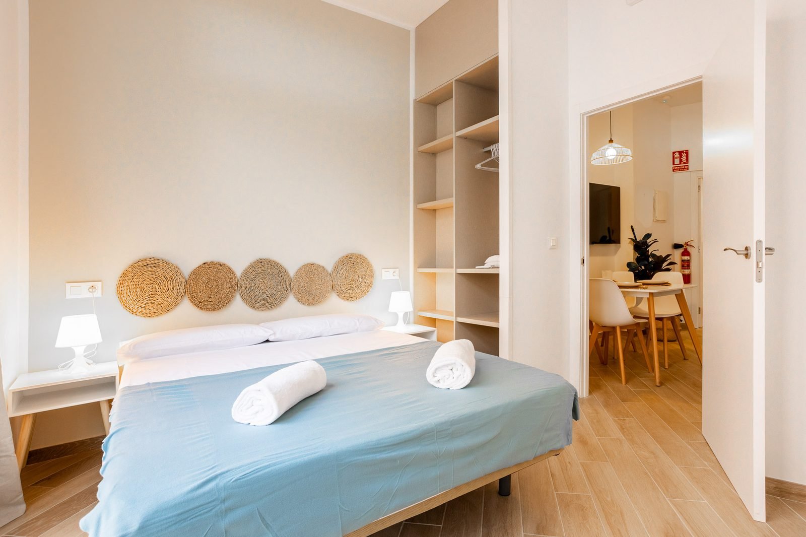 Dormitorio con armario abierto y vista hacia el salón y la cocina