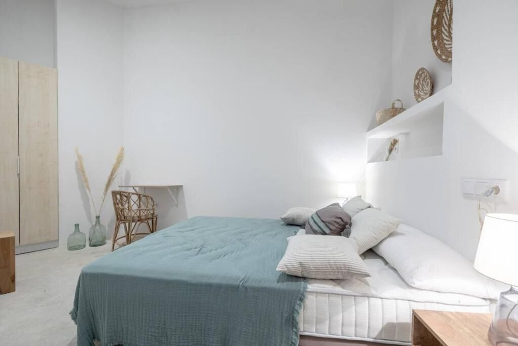 Dormitorio en planta baja con cama, estanterías decorativas y escritorio