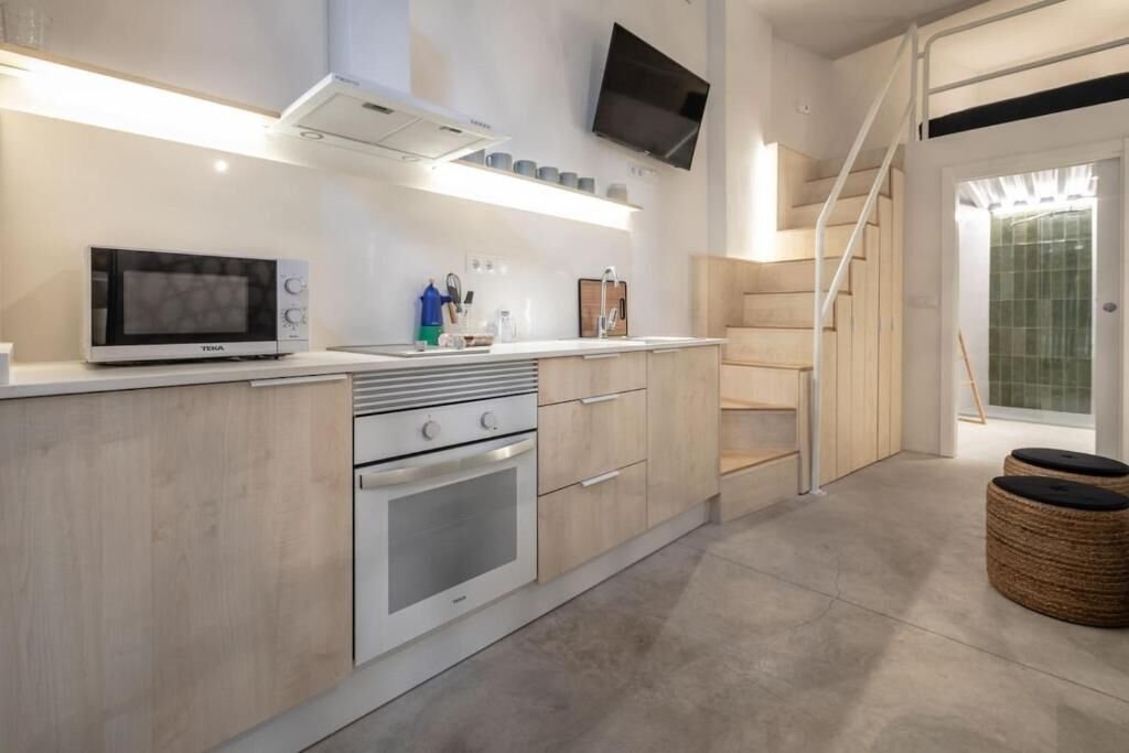Cocina equipada con horno, microondas, placa y escalera de acceso al altillo