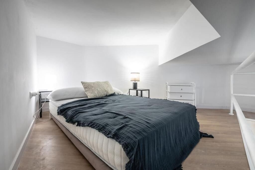 Dormitorio del altillo con ropa de cama verde oscuro bajo un lucernario
