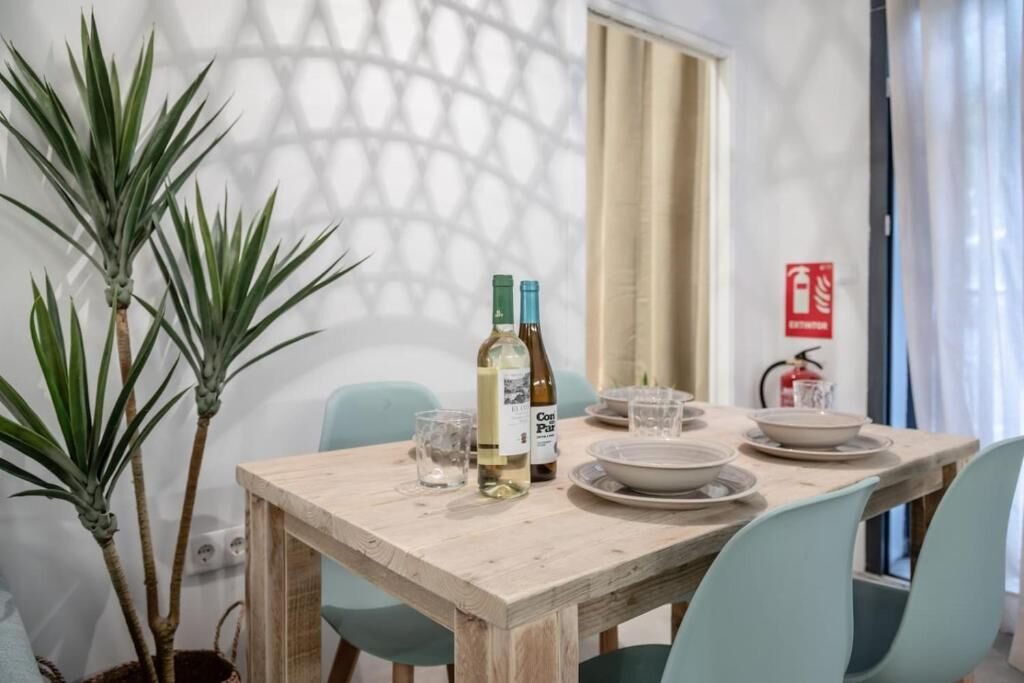 Mesa de comedor puesta con vajilla, copas y una botella de vino