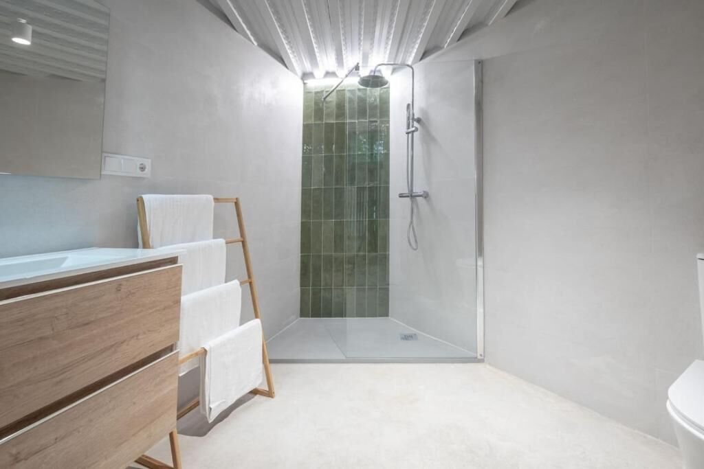 Ducha con mampara de cristal y azulejo verde en el baño